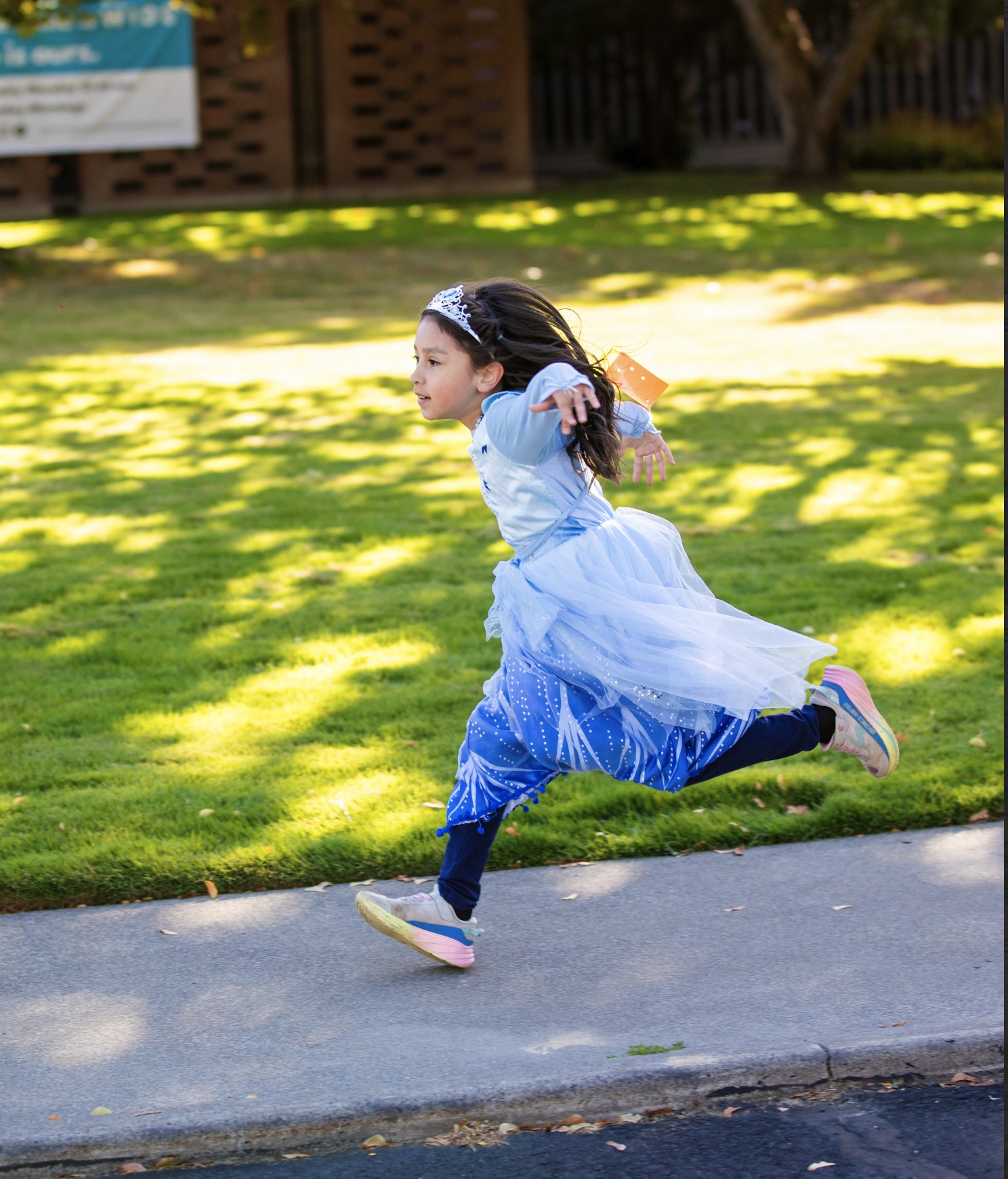 An MSY student running in a blue costume during a school event