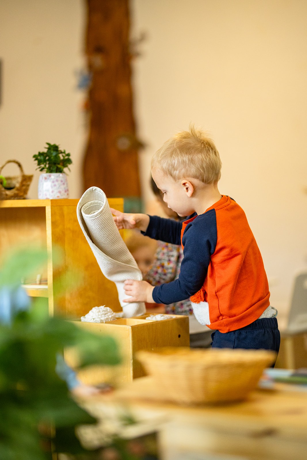 A toddler rolling a classroom work mat